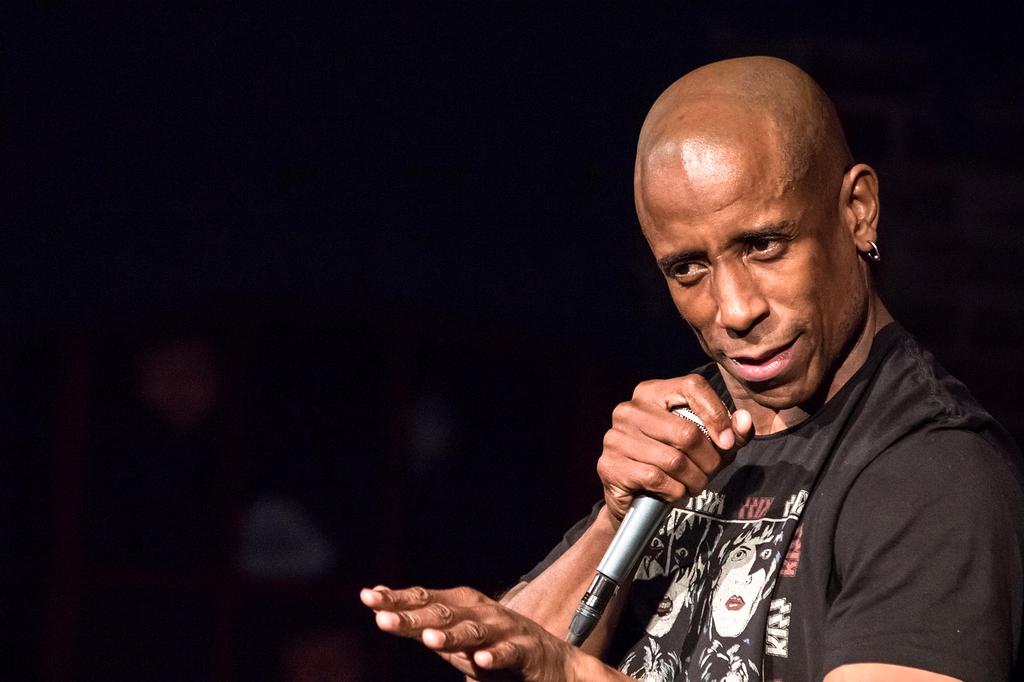 Stand-up comedian on stage with microphone entertaining laughing audience